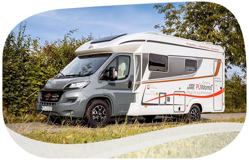 Außenansicht des PflegeübungsWohnmobils PÜWomo auf einer Landstraße